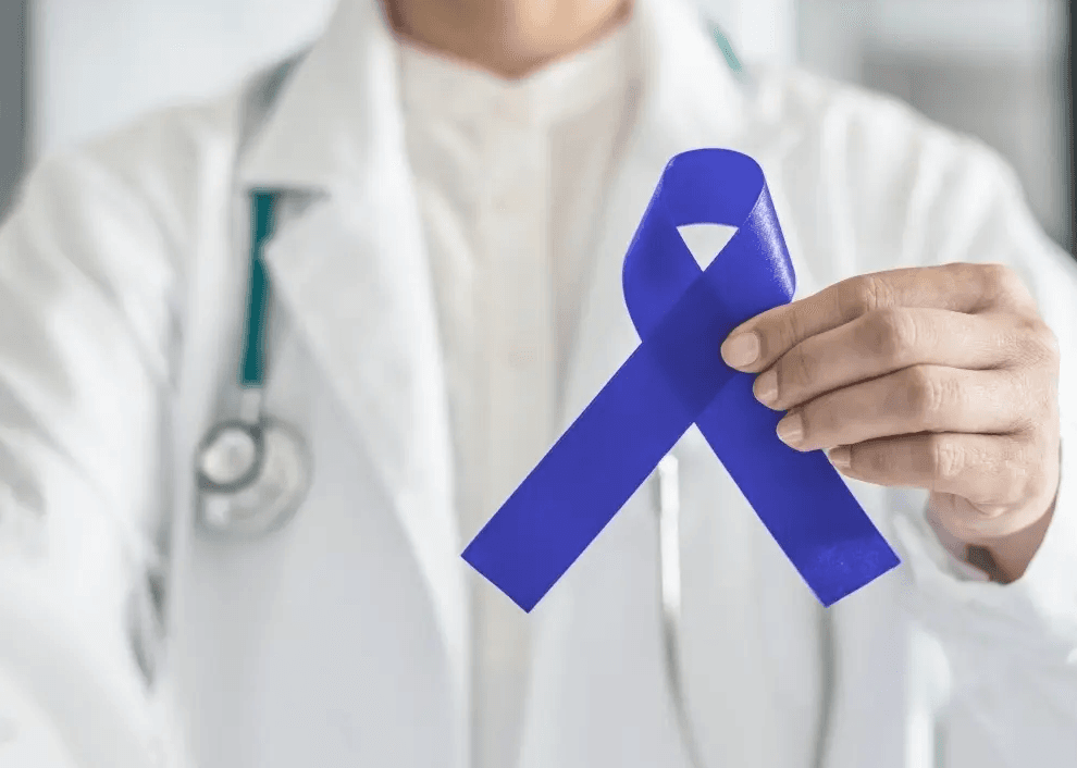 Doctor in white coat with stethoscope holding a blue awareness ribbon.