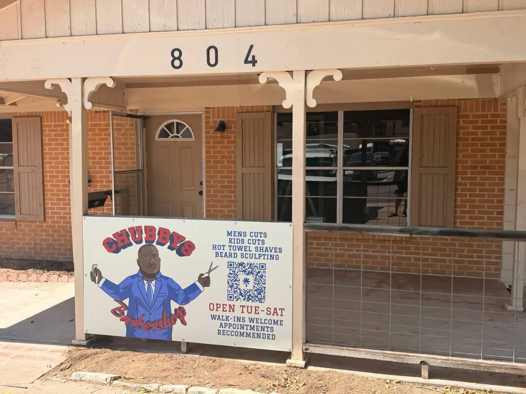 Chubby's Barbershop sign listing services outside brick building numbered 804 with covered porch.