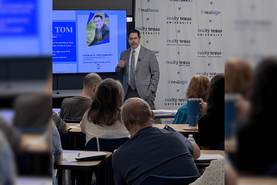 Man in gray suit presents to seated audience beside a screen displaying attorney Thomas D. Fortenberry's bio.