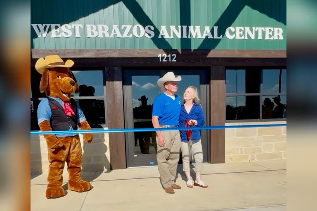 Couple and dog mascot in cowboy hats at ribbon-cutting outside West Brazos Animal Center.