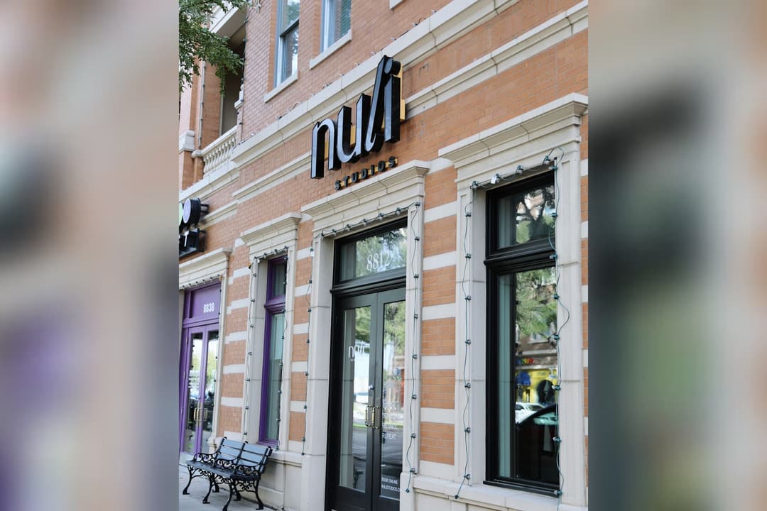 Exterior of Nuli Studios at 8812, a brick storefront with glass doors and a bench out front.