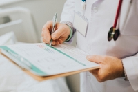 doctor writing on a clipboard adobe stock image