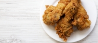 Fried chicken drumsticks on a white round plate, top view. From above, overhead, flat lay. Copy space.