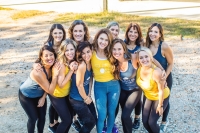 A photo of a group of women huddled together in yellow and blue fitness gear.