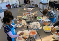 A photo of several children cooking with aprons on.