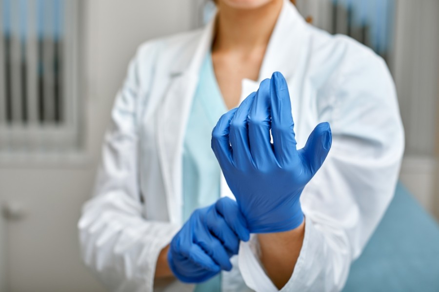 Photo of a female physician putting on blue latex gloves