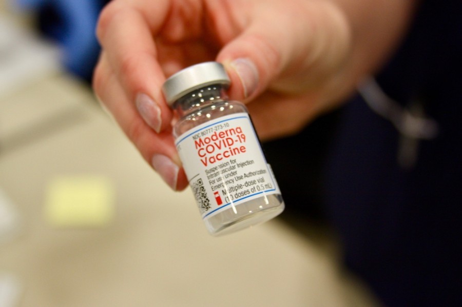 Photo of a hand holding a vial of Moderna vaccine