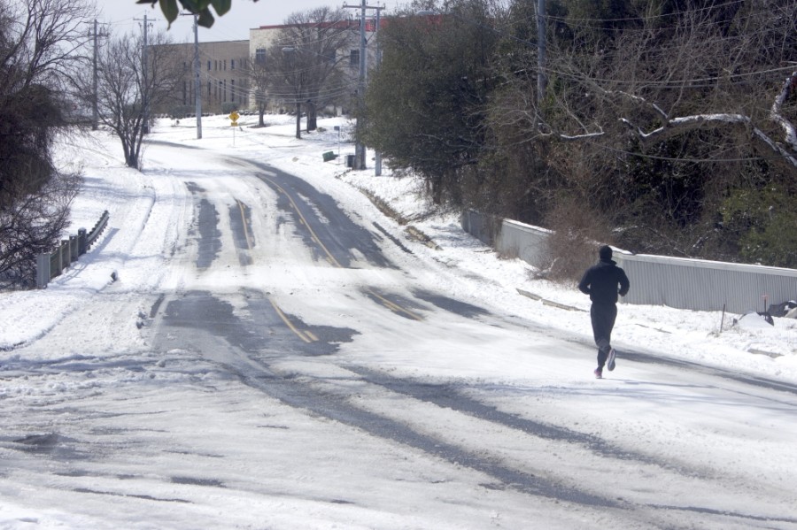 A lone runner jogs on a snow-covered road in Austin. Transportation projects across the city were briefly paused due to Winter Storm Uri. (Jack Flagler/Community Impact Newspaper)