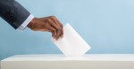 hand dropping voter ballot into box