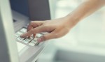 A hand typing on an ATM keypad