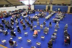 Photo of people receiving vaccines in a gym