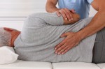 A man on his side. A doctor is rubbing his back.
