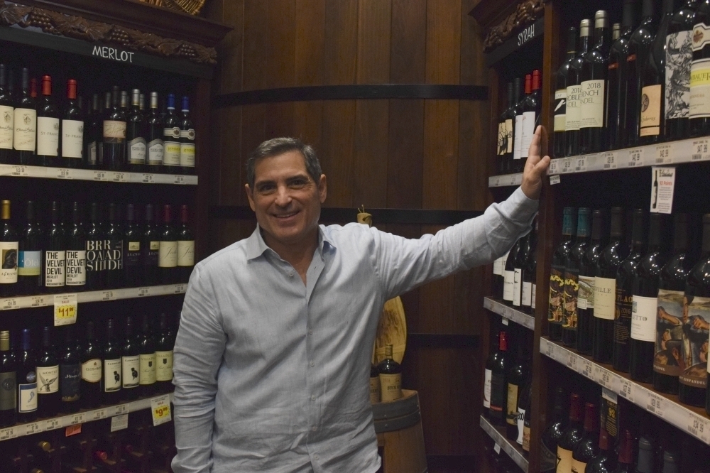 owner Randy Johnson stands next to some of the wine bottles his store has for sale