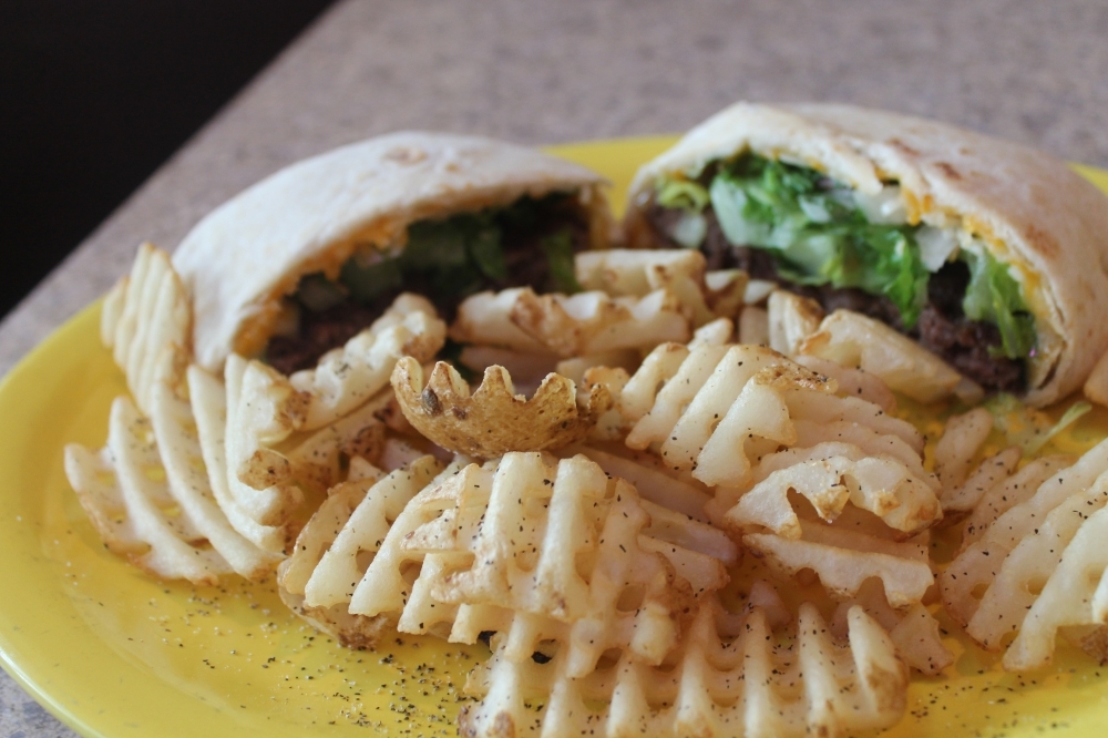The quesadilla burger ($12) comes wrapped in a homemade flour tortilla. (Colleen Ferguson/Community Impact Newspaper)