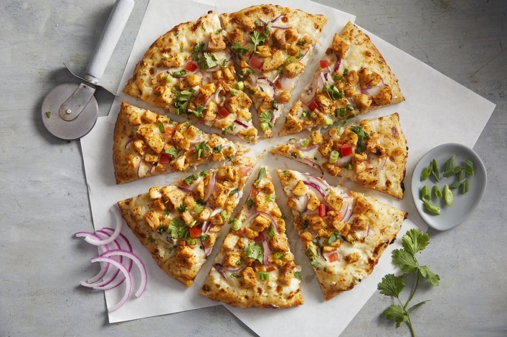 Curry Pizza House's chicken tikka pizza includes a white garlic sauce, cheese, red onion, diced tomatoes, tikka chicken, green onion and cilantro. (Courtesy Curry Pizza House)