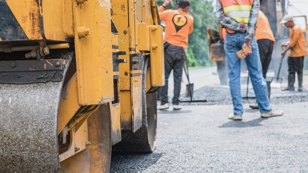 Small asphalt roller in on duty repairing repairing asphalt road. Workers on a road construction