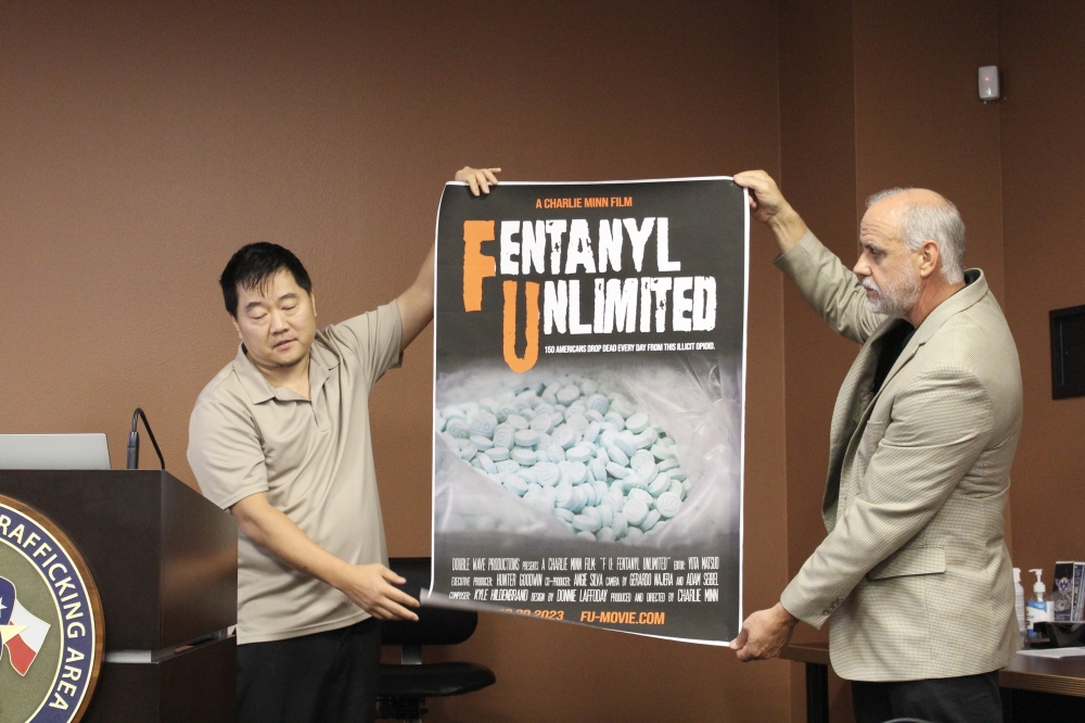 Director Charlie Minn, left, displays the documentary's promotional poster. (Danica Lloyd/Community Impact)