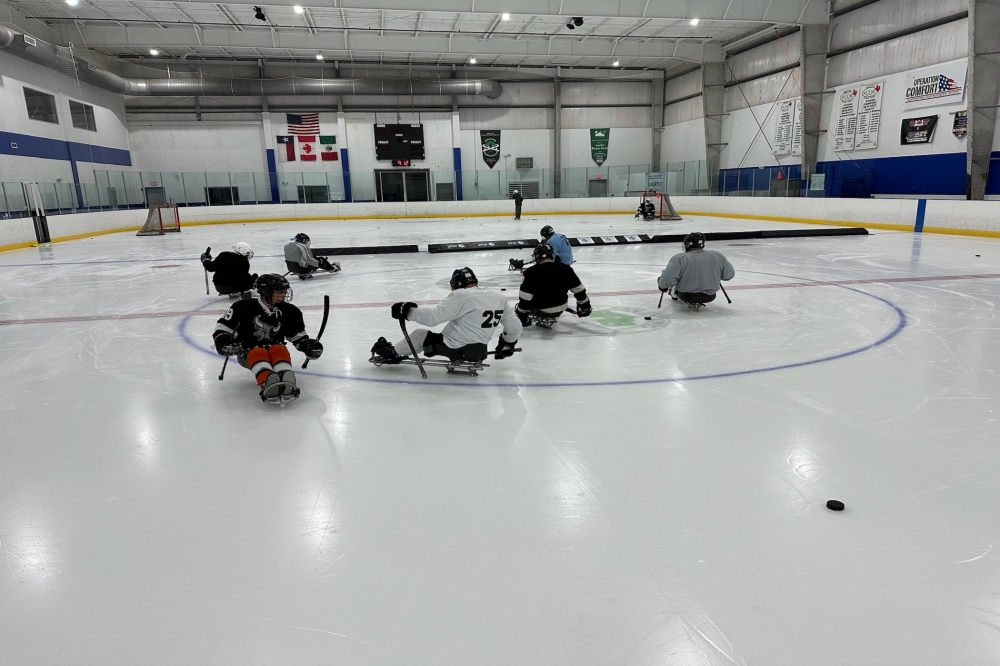 Team members playing sled hockey.