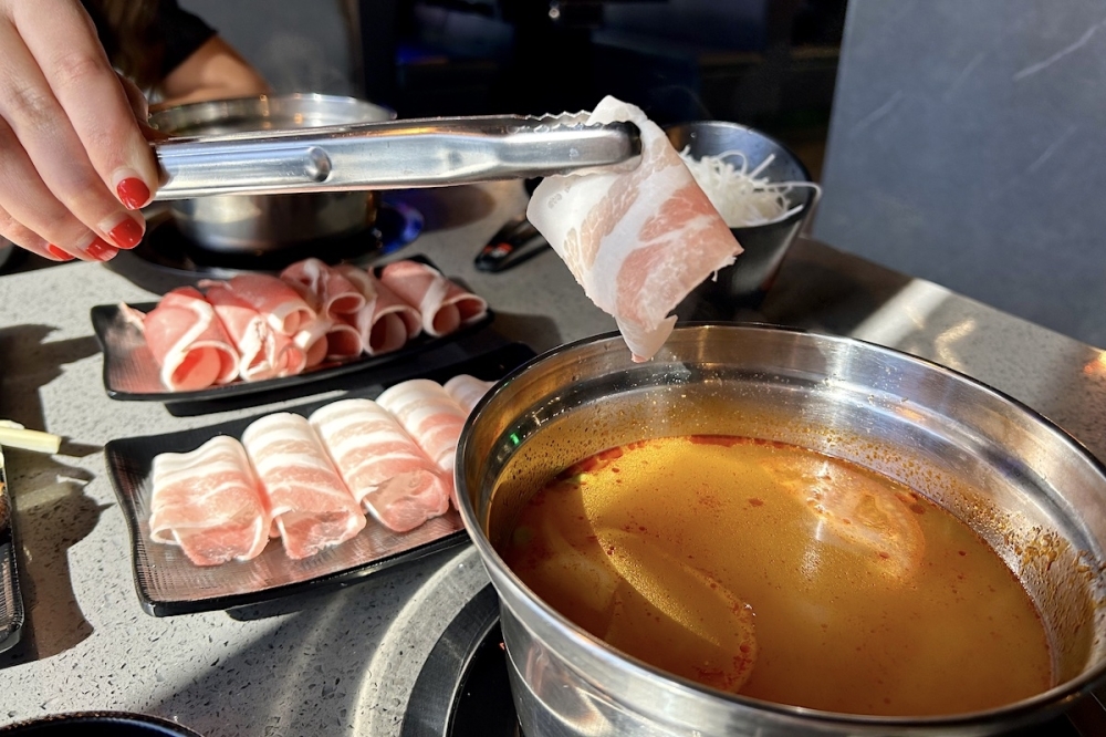 The hot pot option at KPot, including a Thai tom yum soup base, sliced pork belly and lamb that is cooked in the soup. (Elle Bent/Community Impact)