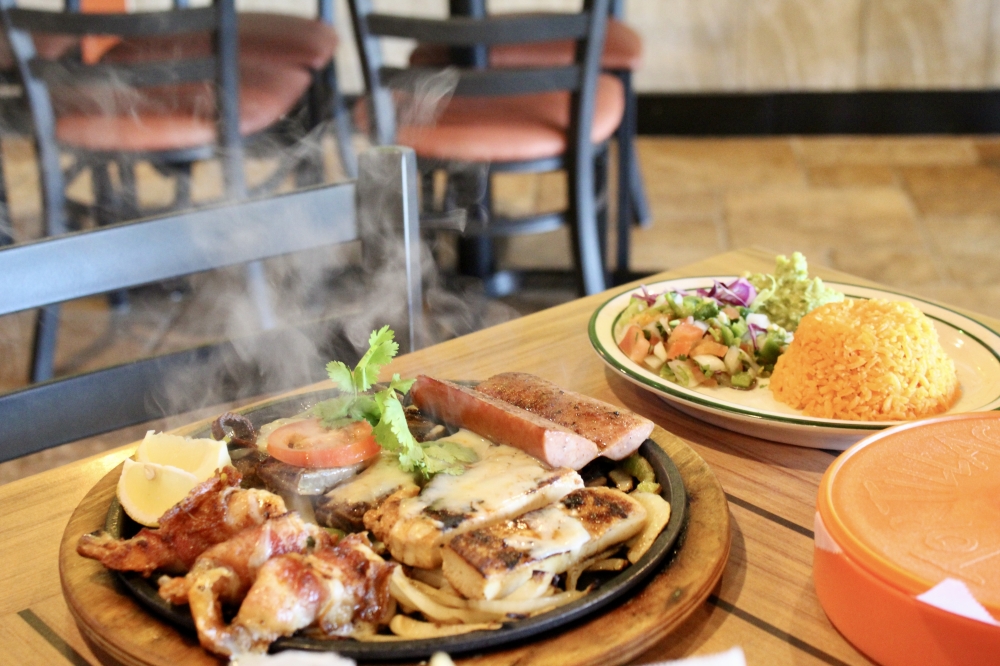 El bueno ($22.99) dish includes three jumbo shrimp wrapped in bacon, chicken, beef and sausage fajitas and are served with rice, beans, guacamole and pico de gallo. (Jovanna Aguilar/Community Impact)