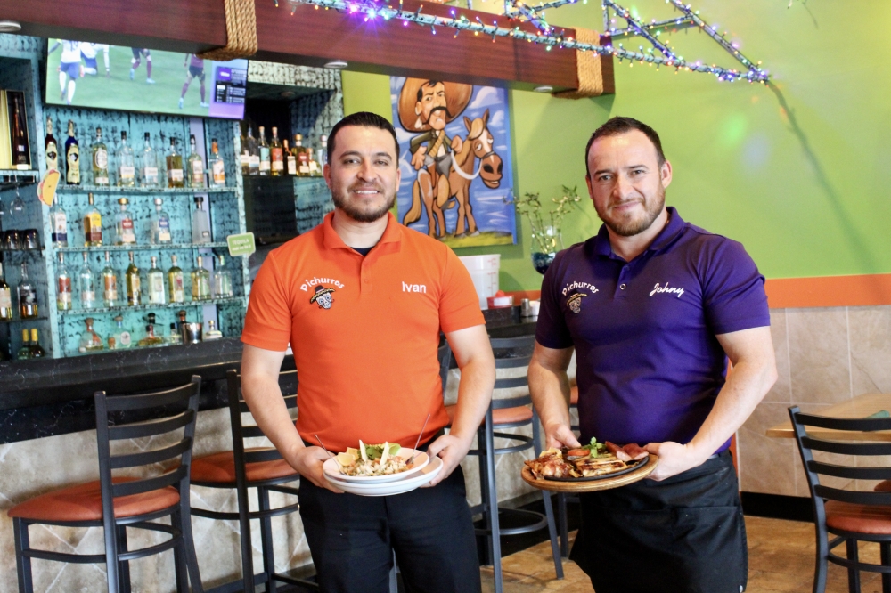 Ivan Aguado and Johny Rodriguez hold ceviche and sizzling fajitas. (Jovanna Aguilar/Community Impact)