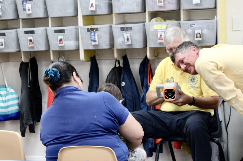 Lions Club’s KidSight licensed screeners Allen Brinkley and Chuck Martin perform a vision screening for a Children's Lighthouse of Houston child on Sept. 12. (Jovanna Aguilar/Community Impact)