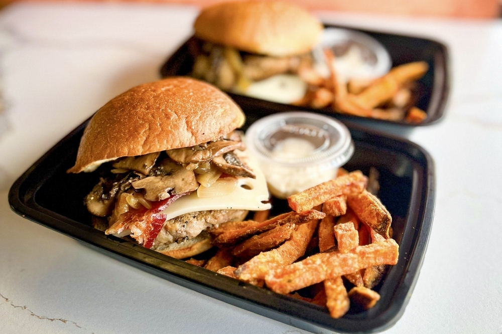 The mushroom swiss truffle burger ($11) includes a grilled turkey burger topped with swiss cheese, sautéed mushrooms, caramelized onions and crispy bacon with a side of sweet potato fries and a crave worthy truffle aioli. (Courtesy Farley's Fit Kitchen)