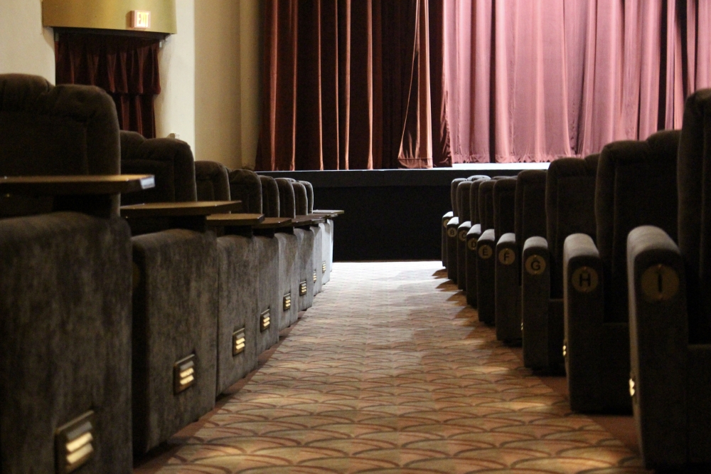 Newly installed theatre seats are a soft plush fabricate with a tray to hold food and drinks, as well as a call button for service. (Cassandra Jenkins/Community Impact)