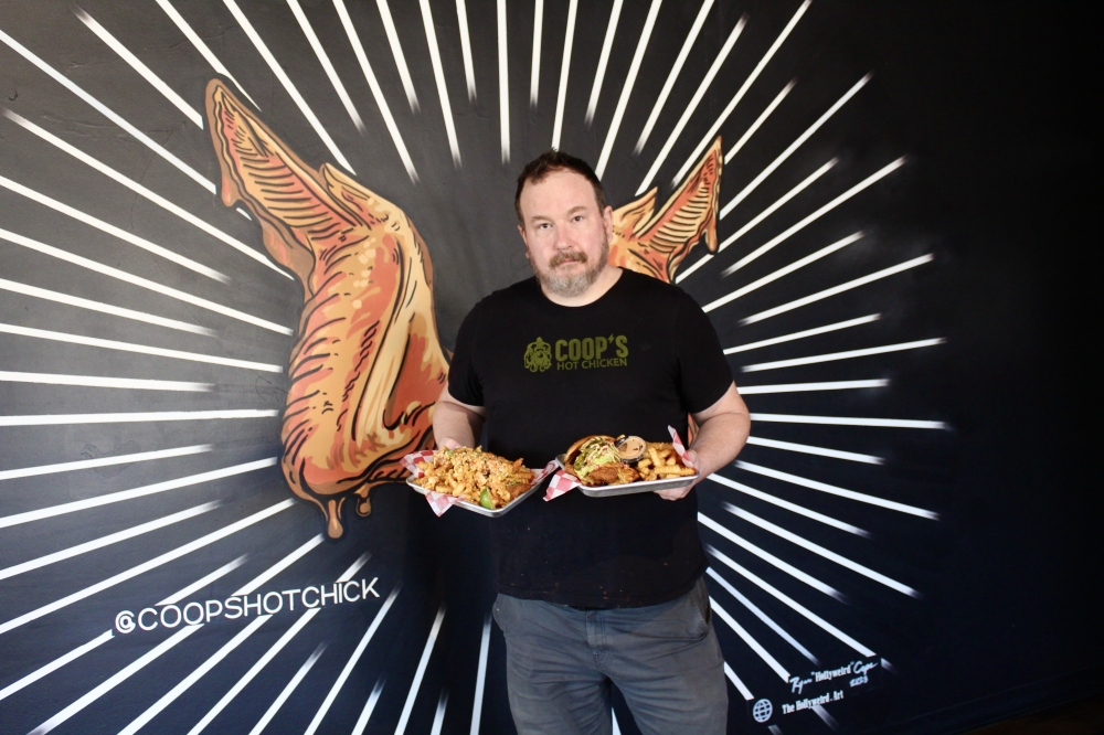 Shawn Ward, Coop's Hot Chicken General Manager holds two restaurant meals. (Jovanna Aguilar/Community Impact)