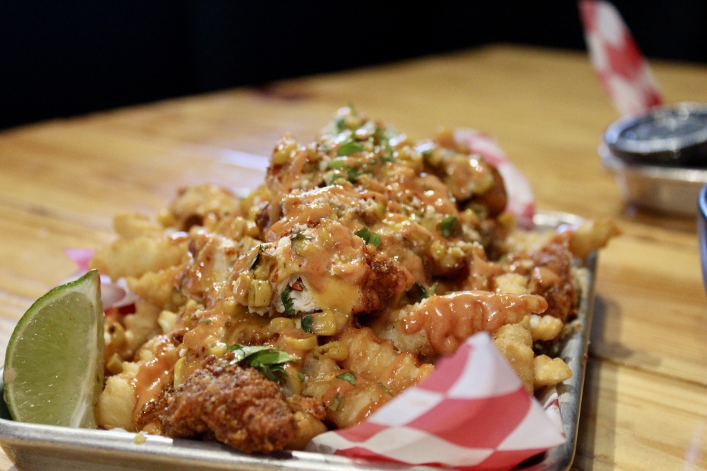 The Hot Chick ($12.99) loaded fries include Nashville hot chicken, queso, roasted corn, cotija, lime, cilantro and Coop's sauce. (Jovanna Aguilar/Community Impact)