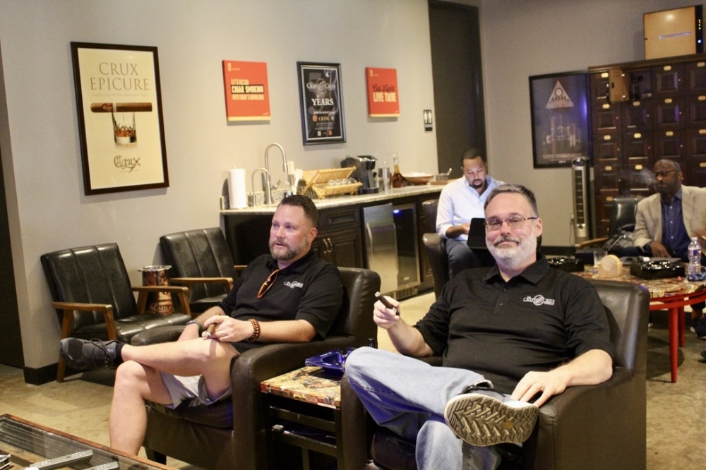 Owners Jason and Justin Currin sit in their VIP cigar lounge with their regulars. (Jovanna Aguilar/Community Impact)