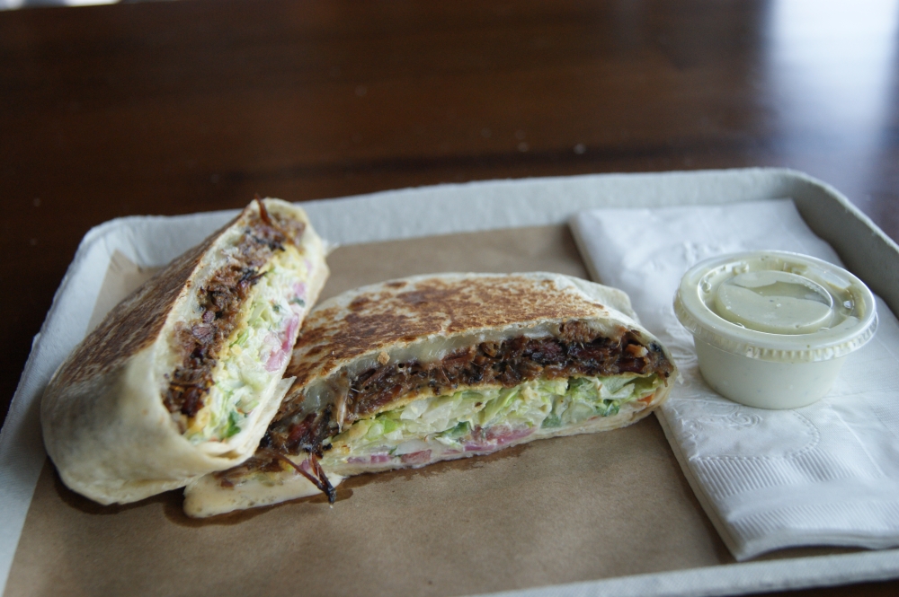 The top-selling brisket crunchwrap combines brisket, monterey jack cheese, a corn tostada, lettuce, pico, queso, pickled onions and salsa verde crema for $19. (Dacia Garcia/Community Impact)