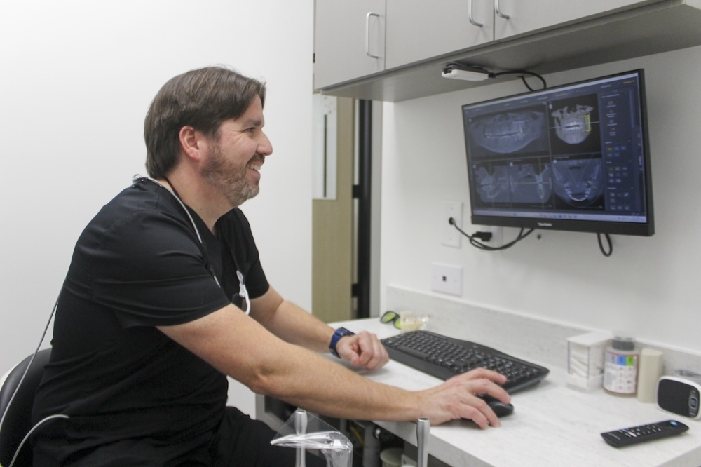 Reach Dental Owner Dr. Luis Orraca analyzes X-rays of teeth. (Amira Van Leeuwen/Community Impact)