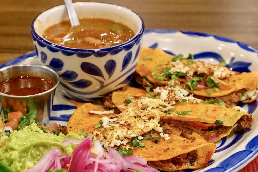 With a recipe created by by Angel Nunez the birria tacos ($18.95) are made with braised marinated short ribs, mexican cheese and are served with pickled onion, guacamole, charro beans and grilled mexican cheese. (Courtesy Juanita's Mexican Kitchen)