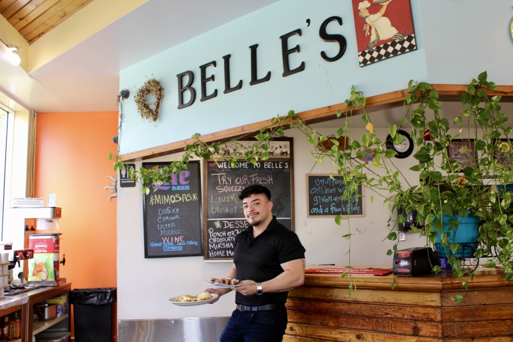 Owner Kevin Calzada holds his diners specialty menu items. (Jovanna Aguilar/Community Impact)