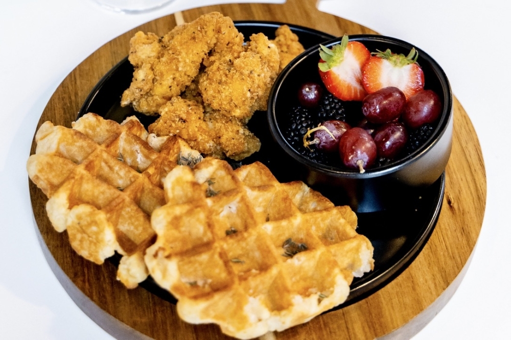 Breakfast items at The Cuterie include chicken and waffles served with fresh fruit. (Courtesy The Cuterie)