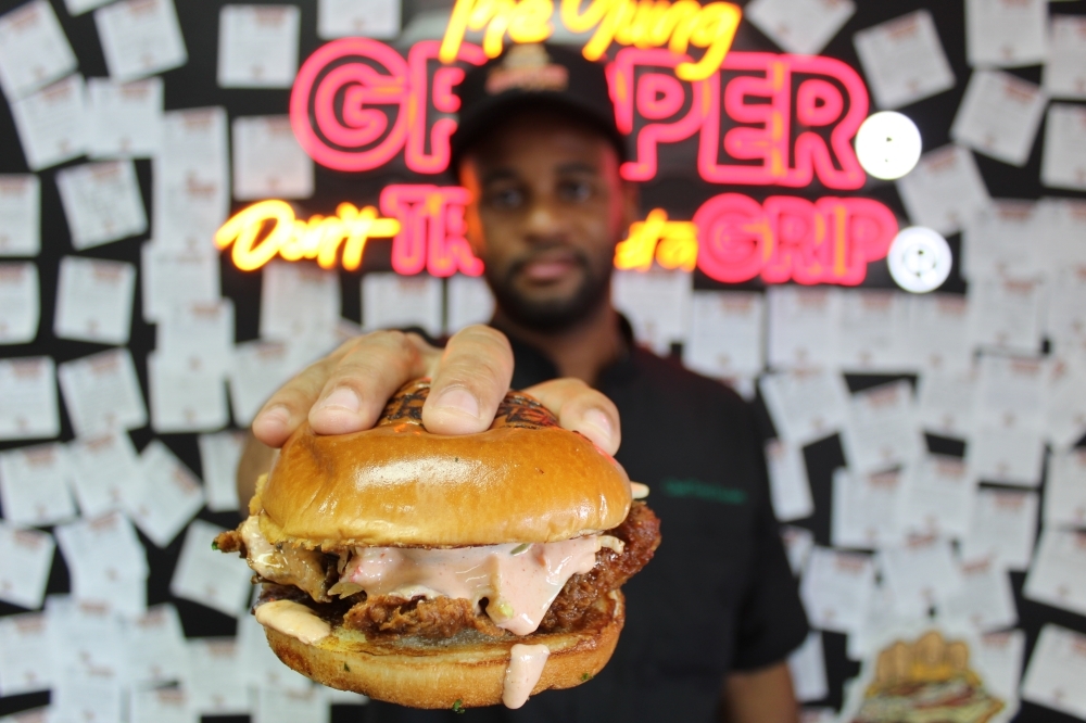 The Gripper Kitchen owner Rytonie Durden performs his signature 'gripper' pose. (Rachel Leland/Community Impact)