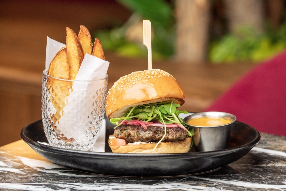 The Kofta Burger at The Lymbar is made with tomato, pickled onion, tzatziki, sesame bun, wedge fries and red curry romesco. (Courtesy Dylan McEwan)