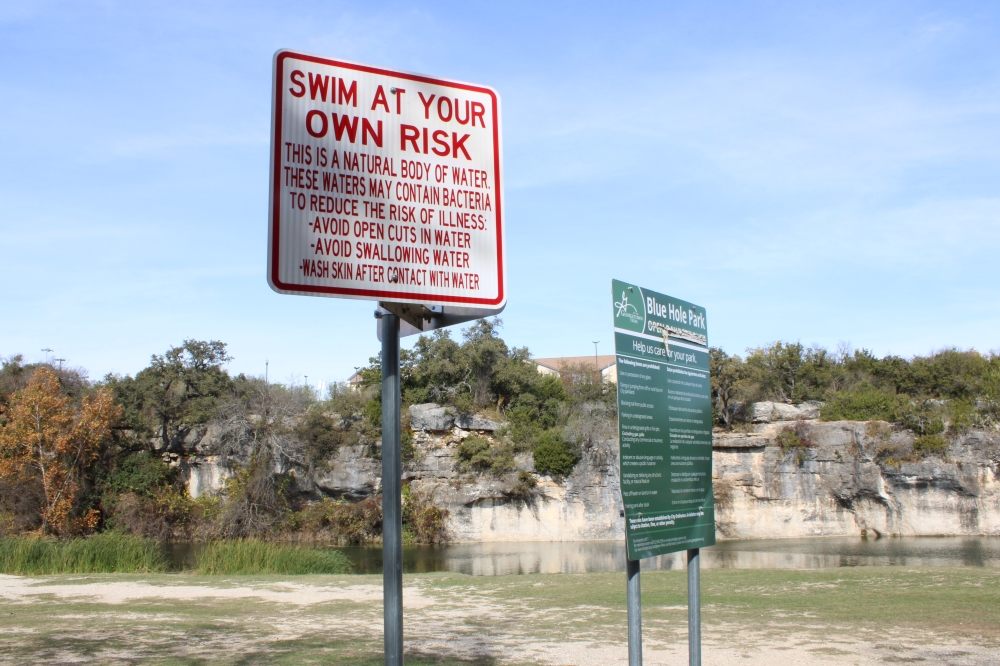 Signs throughout the park warn the water could contain bacteria and suggest people should wash skin if they get in contact with it. (Anna Maness/Community Impact)