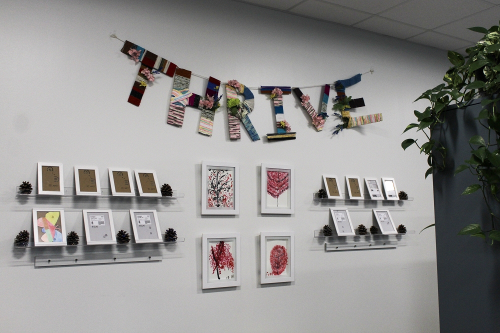 Participants at the AGE of Central Texas Thrive and Social Wellness Center can make art with AGE staff, such as the 'Thrive' sign made with cardboard and string and finger paintings, center. AGE staff said they are eager to showcase more art. (Elisabeth Jimenez/Community Impact)