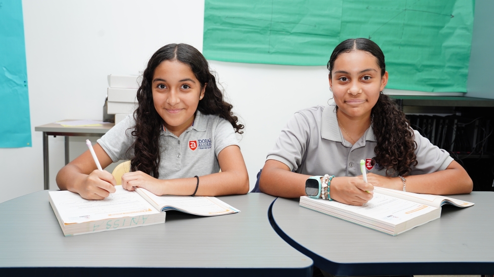 Middle school students in STEM classroom smile and work on school work
