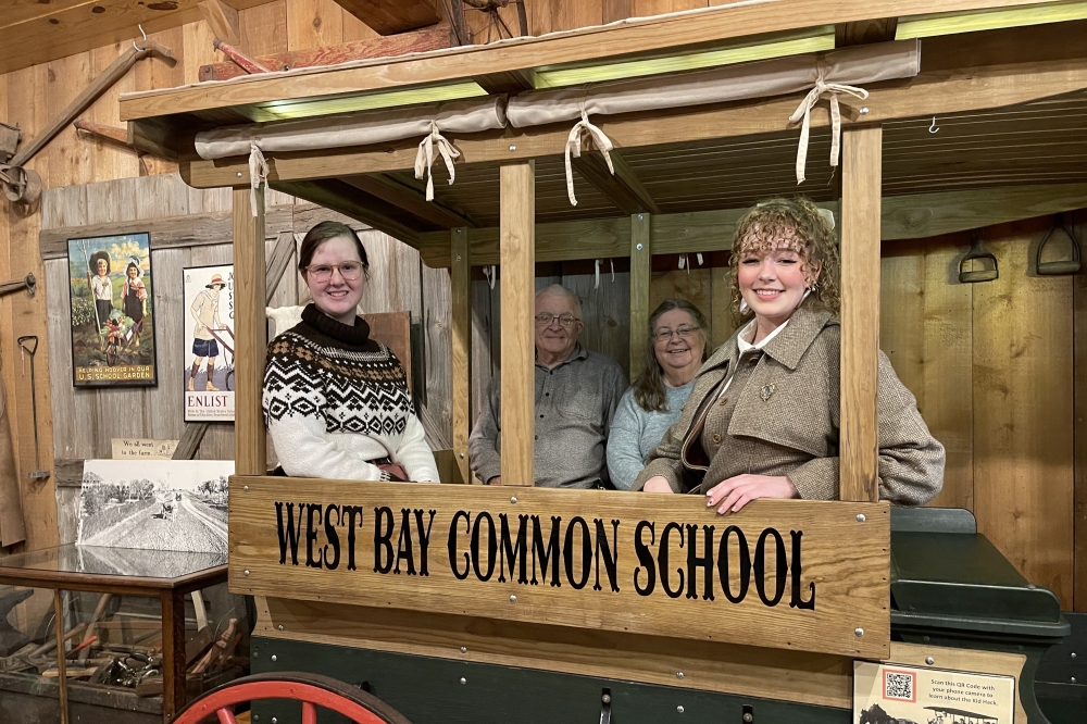 From left to right, Emma Halliburton, Richard Lewis, Catharin Lewis and Maranda Hart sit in an old horse-drawn bus used to transport students to school in the early 20th century. (James T. Norman/Community Impact)