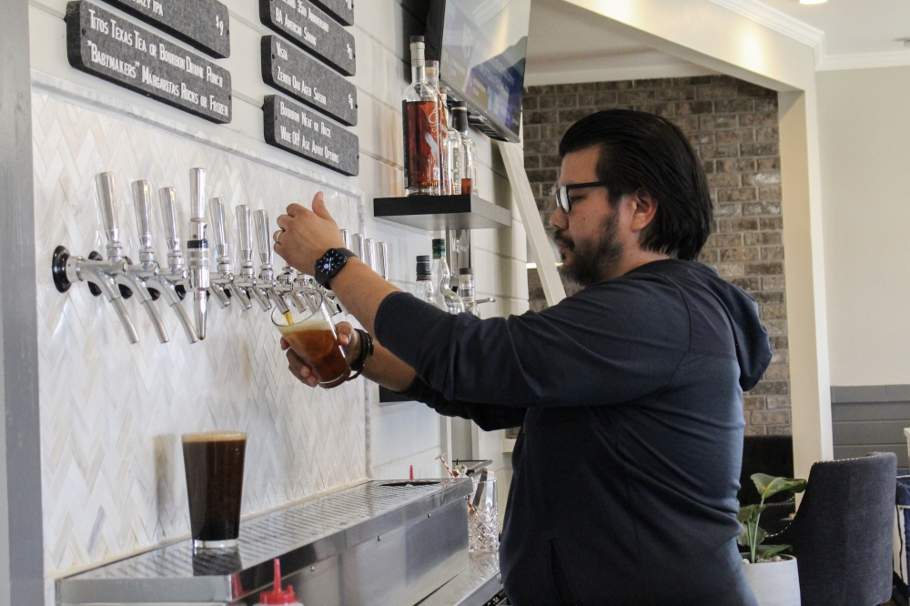 Mercer St. Taproom offers 18 taps, including local Austin beers and other state, national and international beers. Co-owner Jay Moreno, center, said he hopes to add a tap or two home-brewed by Mercer St. Taproom. (Elisabeth Jimenez/Community Impact)