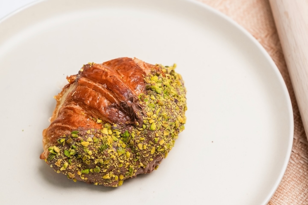 Dubai chocolate croissants, which are filled with knafeh and pistachio, coated in chocolate and sprinkled with crushed pistachios, are a popular item at The Baker's Son. (Courtesy The Baker's Son)