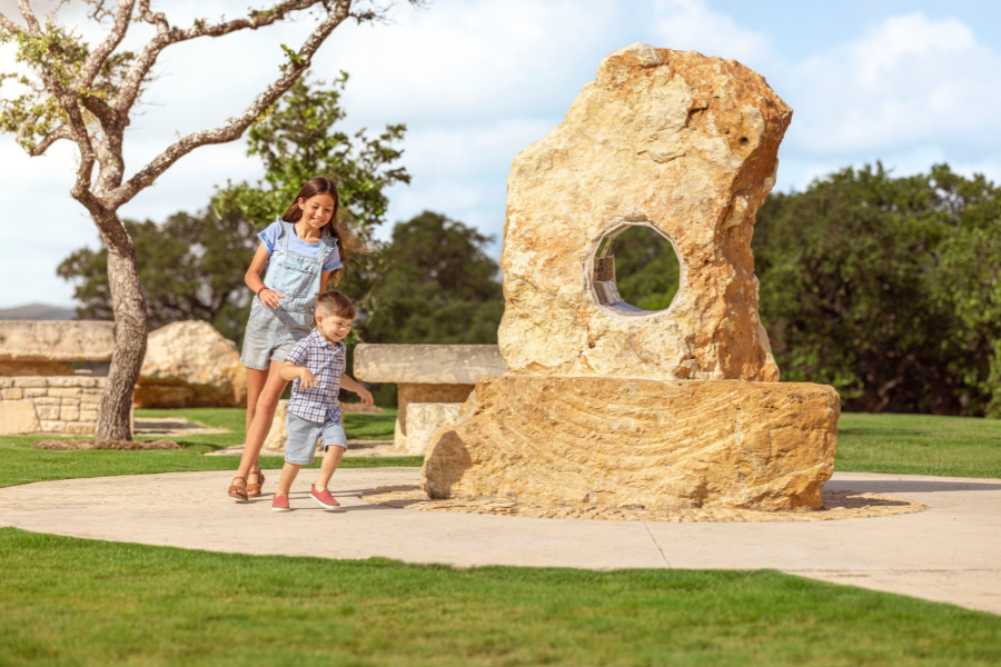 Kids playing by a statue in new home community in Boerne