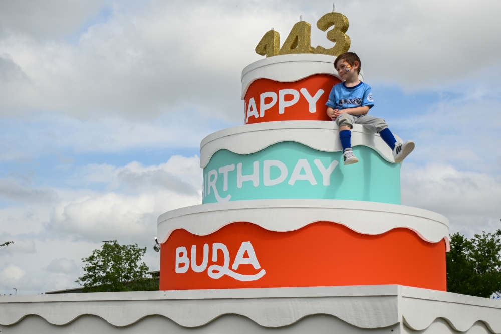 A child sits utop the Buda birthday cake during the Buda 143rd Birthday celebration in Buda, Texas on April 6th, 2024.