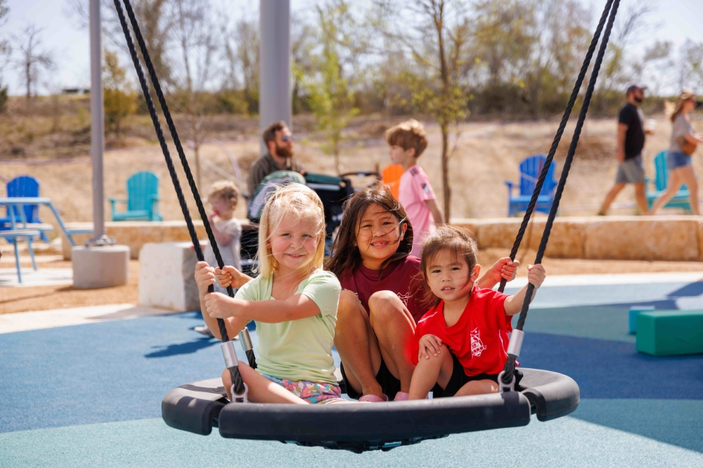 Children playing on a swing at Mayfair's Mayfest festival and home tour event