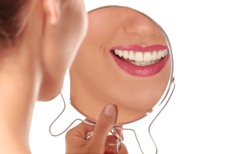 Woman smiles in mirror after seeing dentist in Hutto