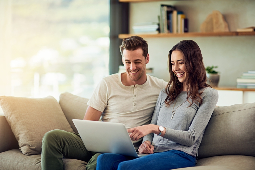 Shot of a happy young couple using a laptop together on the sofa at home