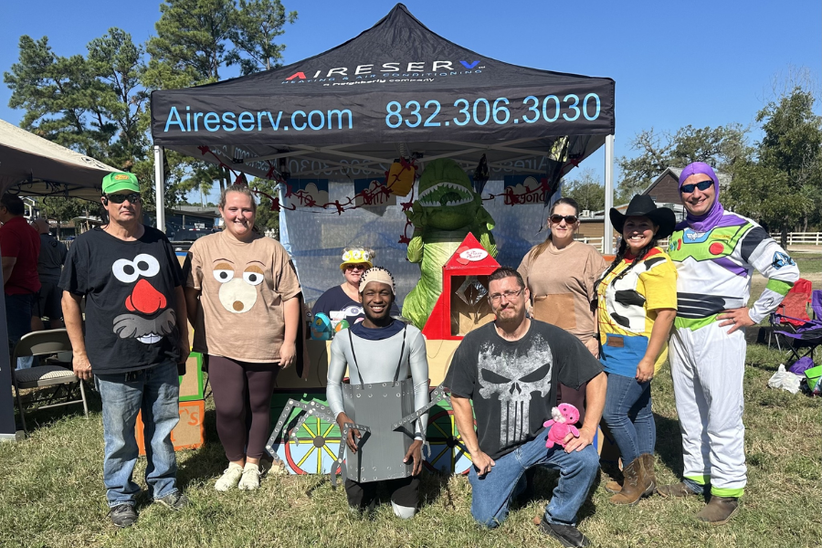 Aire Serv of Houston Northwest team dressed in Toy Story costumes at a community event under a branded tent, showcasing their fun company culture and local HVAC service engagement